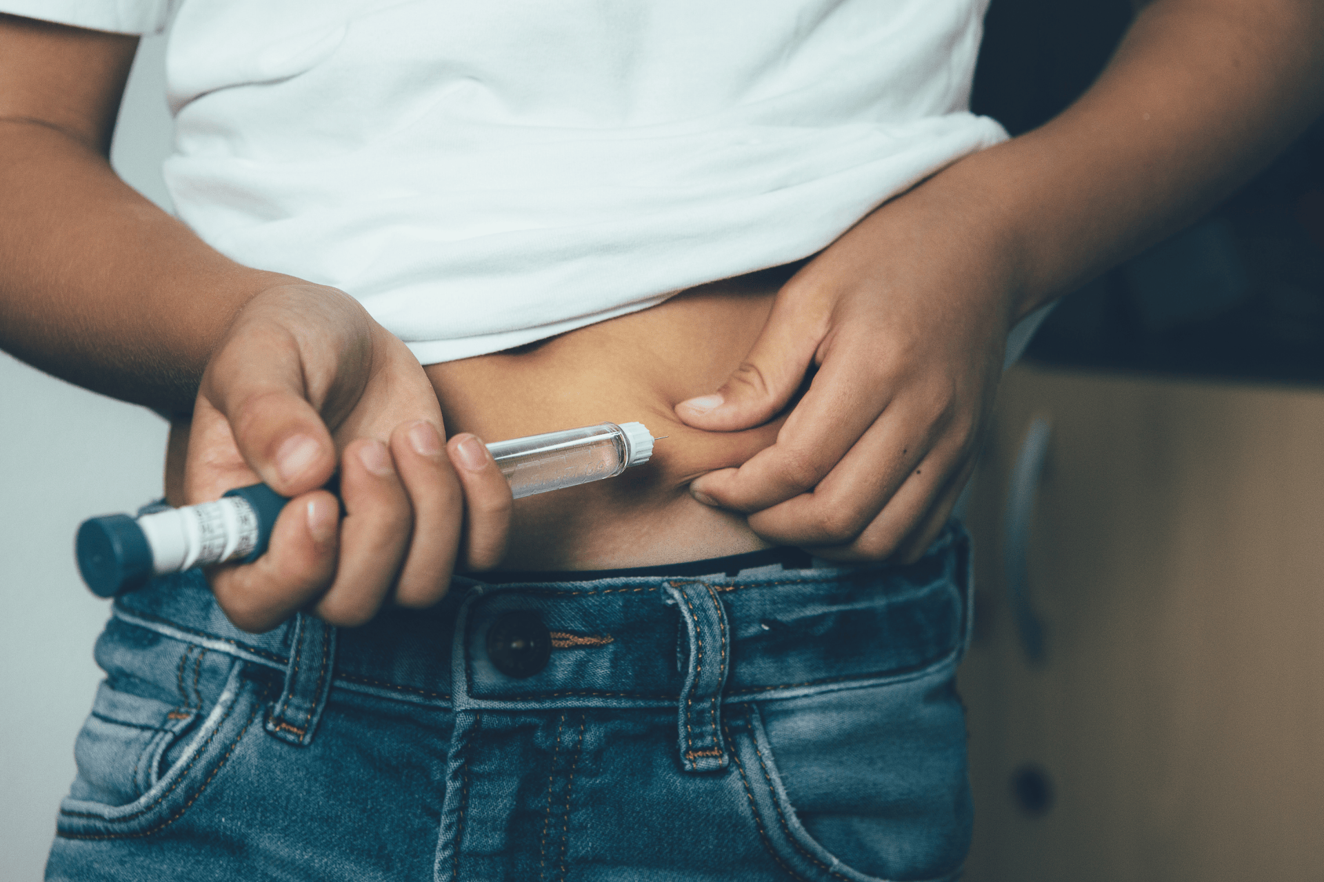 Person injecting insulin into their abdomen using an insulin pen.