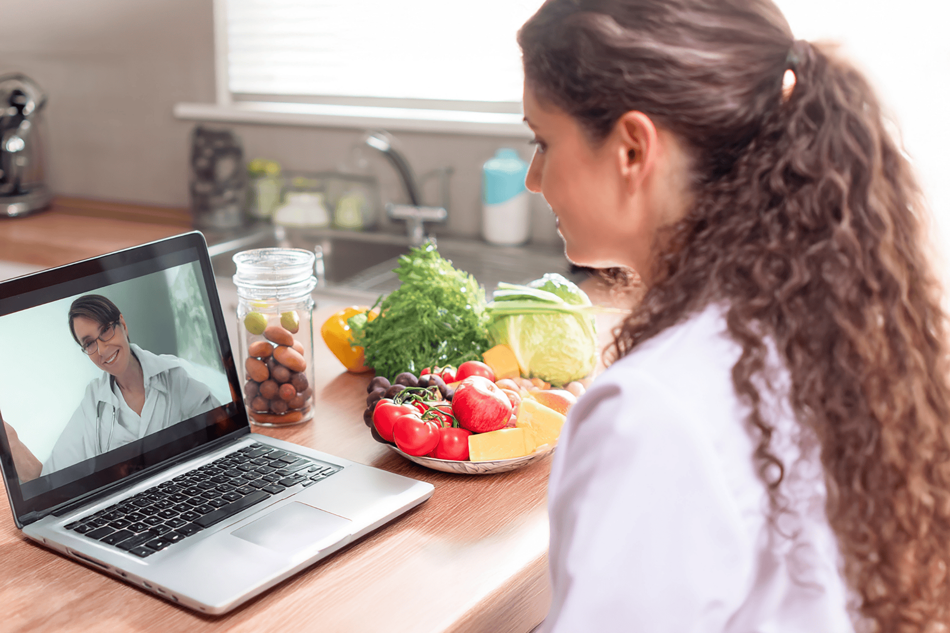 Woman having an online consultation with healthy foods on the counter.