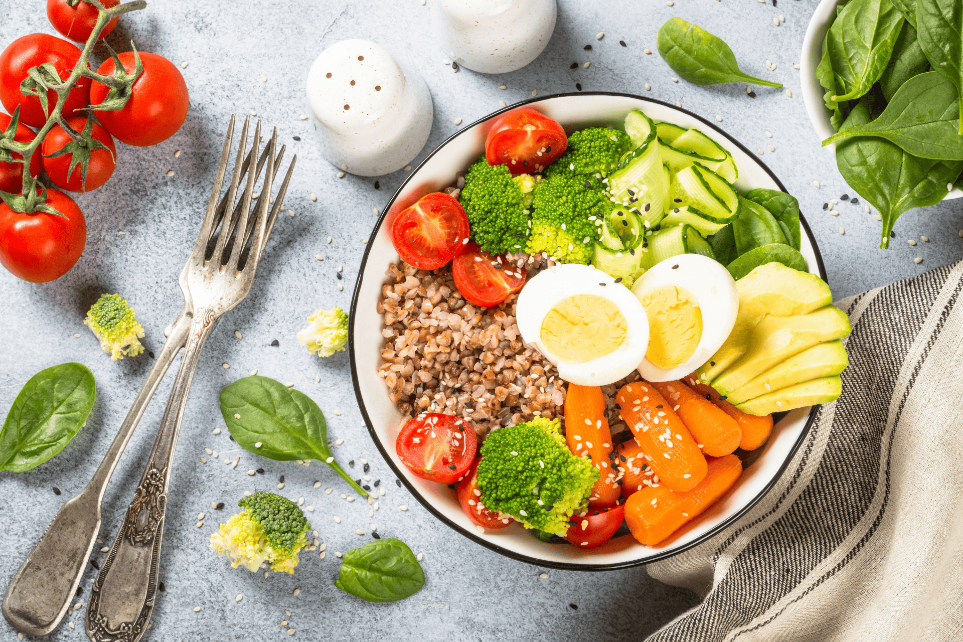 Colorful bowl of fresh vegetables, grains, and boiled eggs arranged on a table.