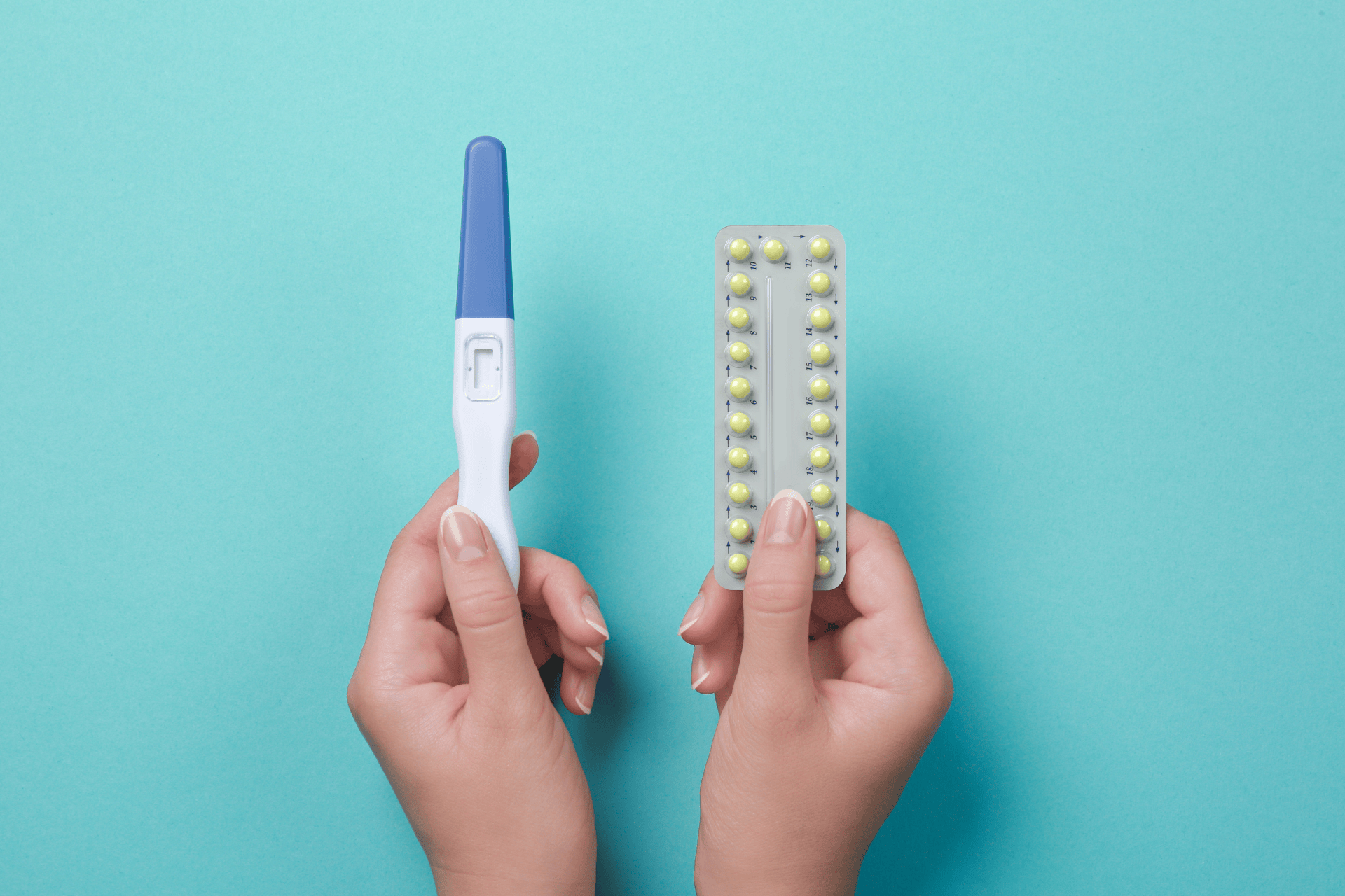 Hands holding a pregnancy test and a pack of birth control pills against a blue background.