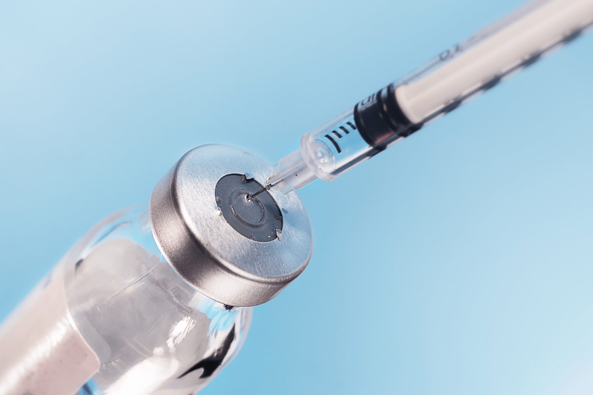 Close-up of a syringe drawing medication from a vial.