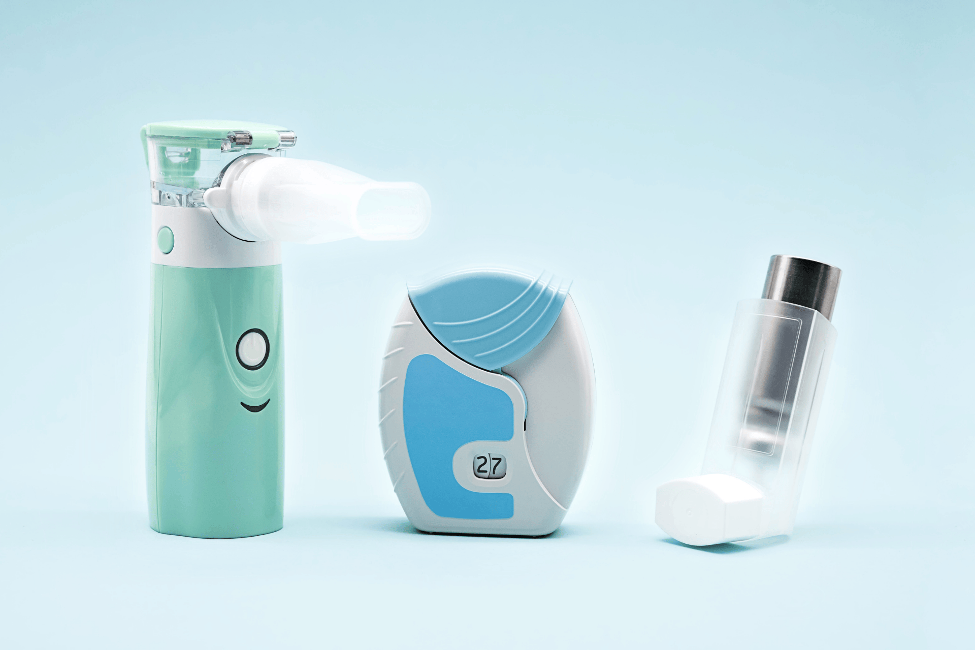 Three smart inhaler devices, including a nebulizer and two digital inhalers, displayed on a light blue background.