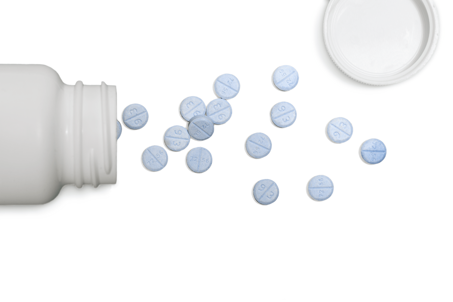 Light blue tablets spilled from a white pill bottle next to its cap on a white background.