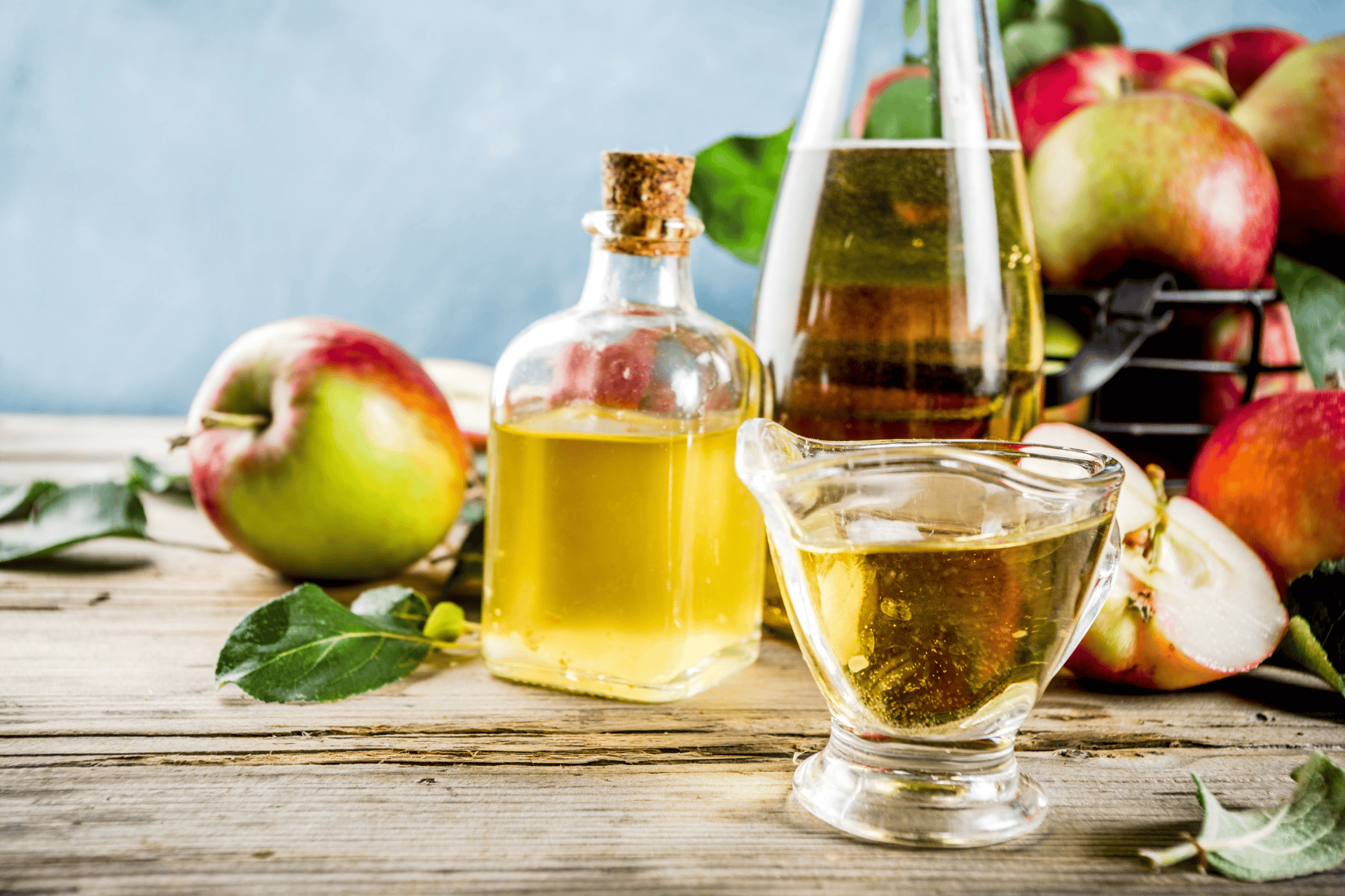 Apple cider vinegar in glass bottles with fresh apples on a wooden table
