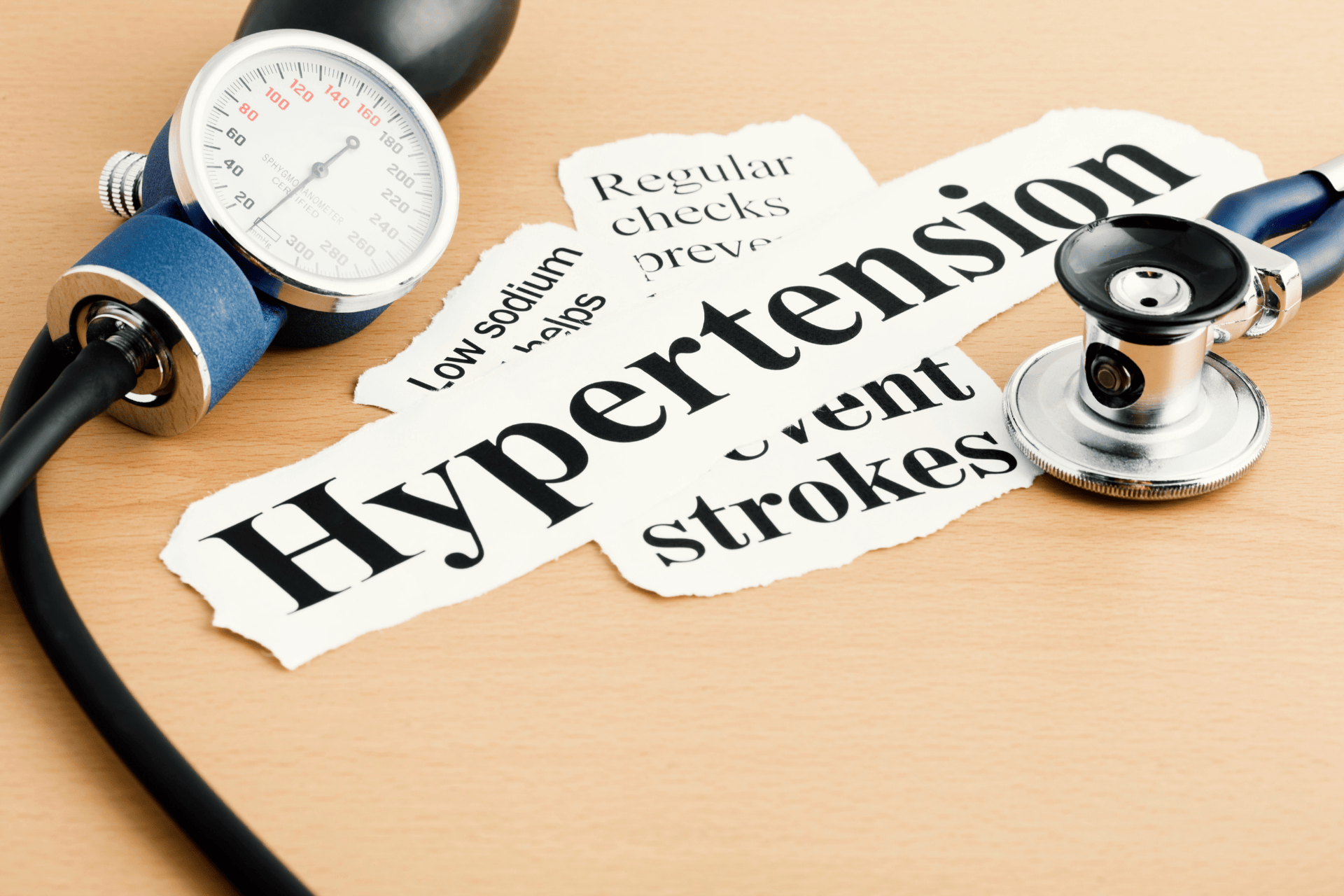 Blood pressure cuff and stethoscope beside the word “Hypertension” on paper.