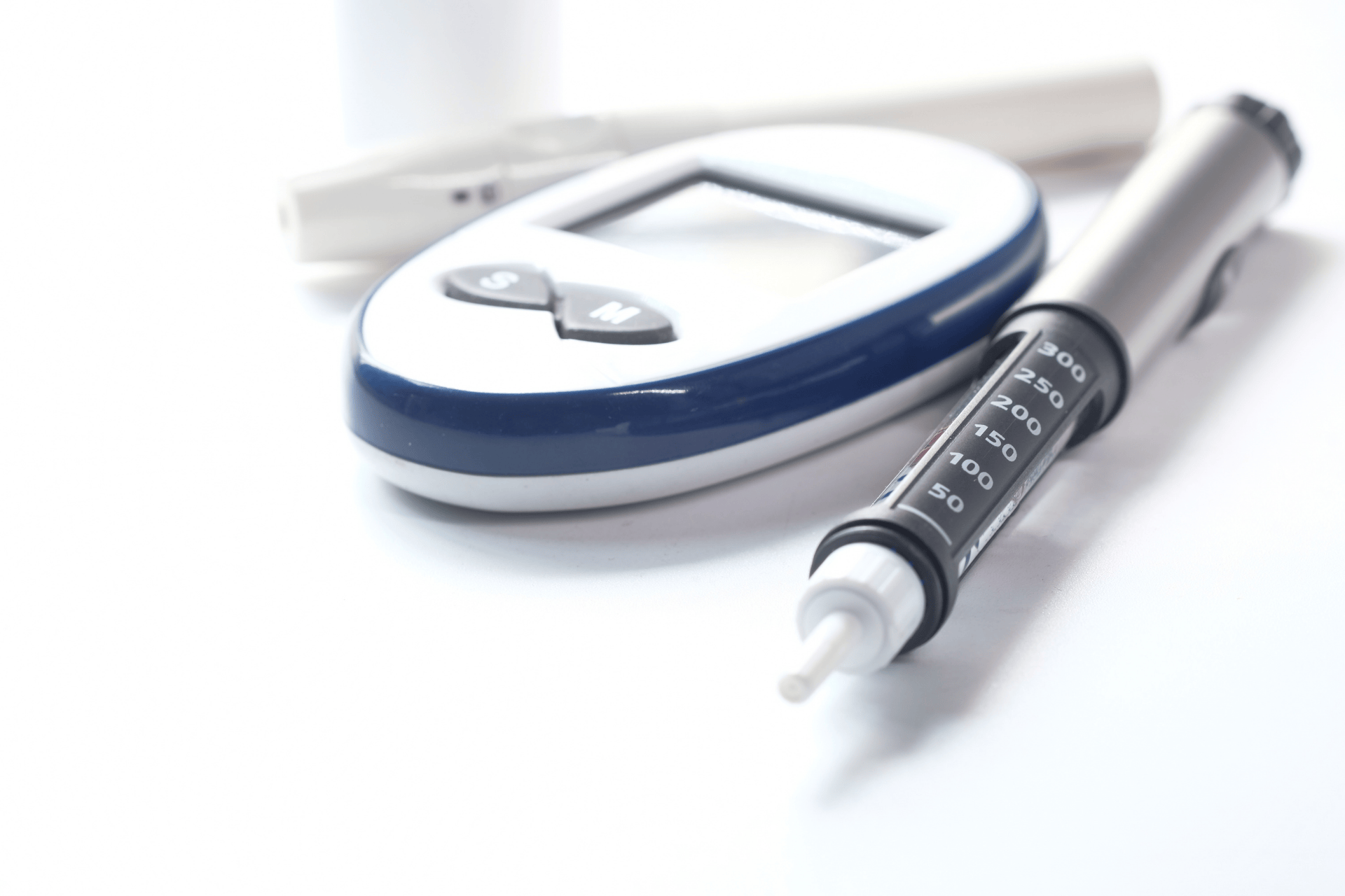 A blood glucose meter and insulin syringe on a white surface.