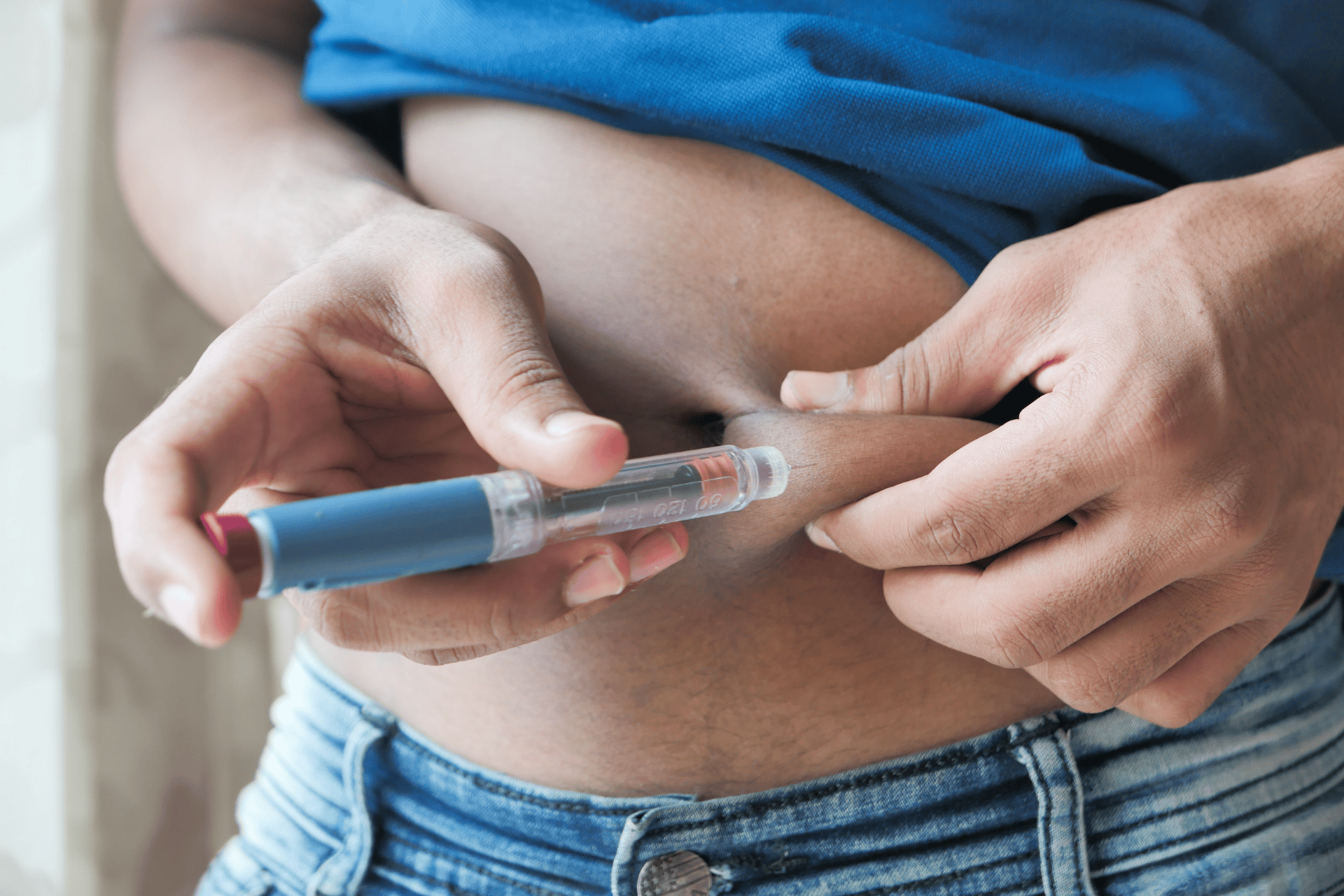 A person injecting insulin into their abdomen using an insulin pen.