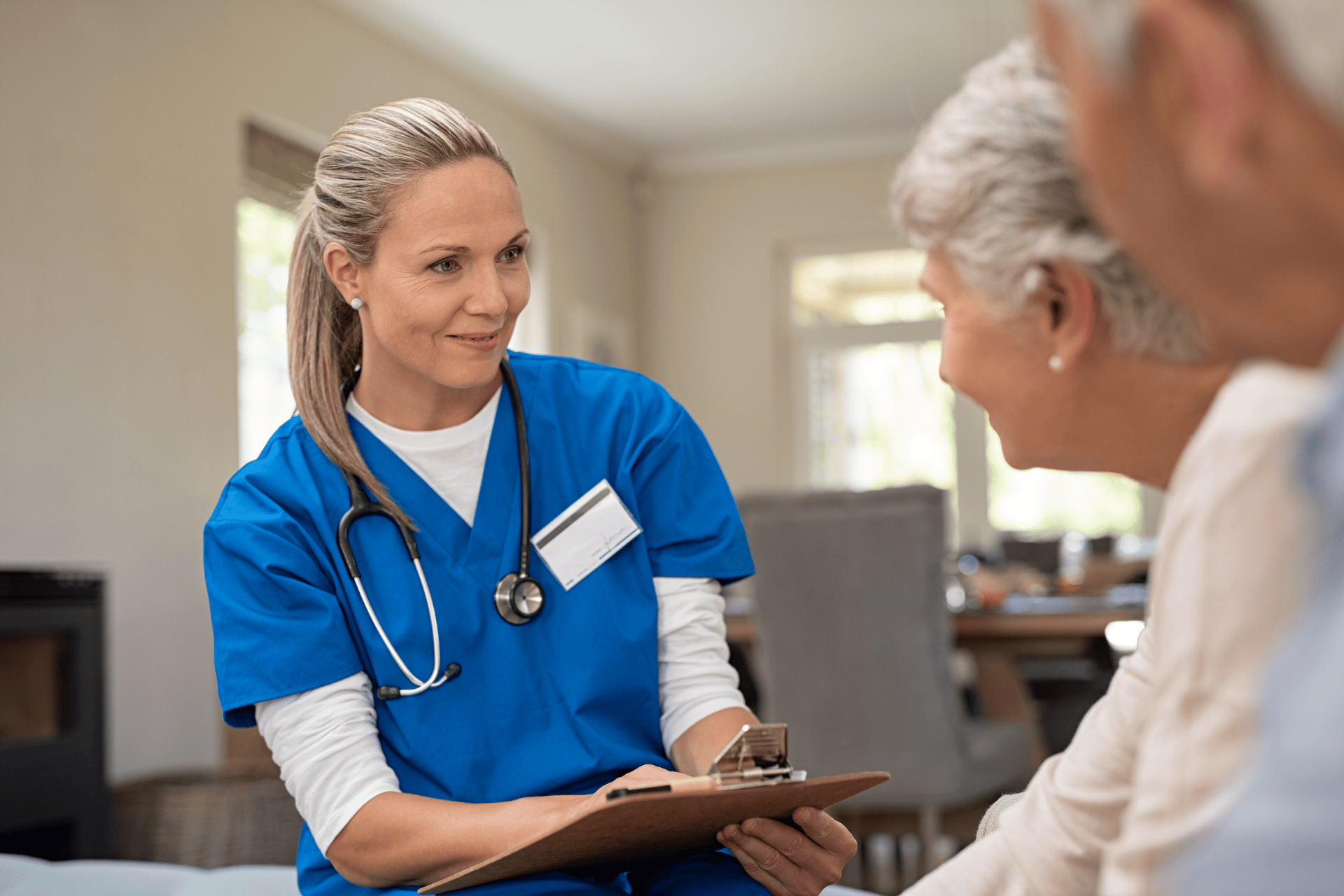 A healthcare professional talking with an older patient, reviewing information on a clipboard, related to dementia care or assessment.