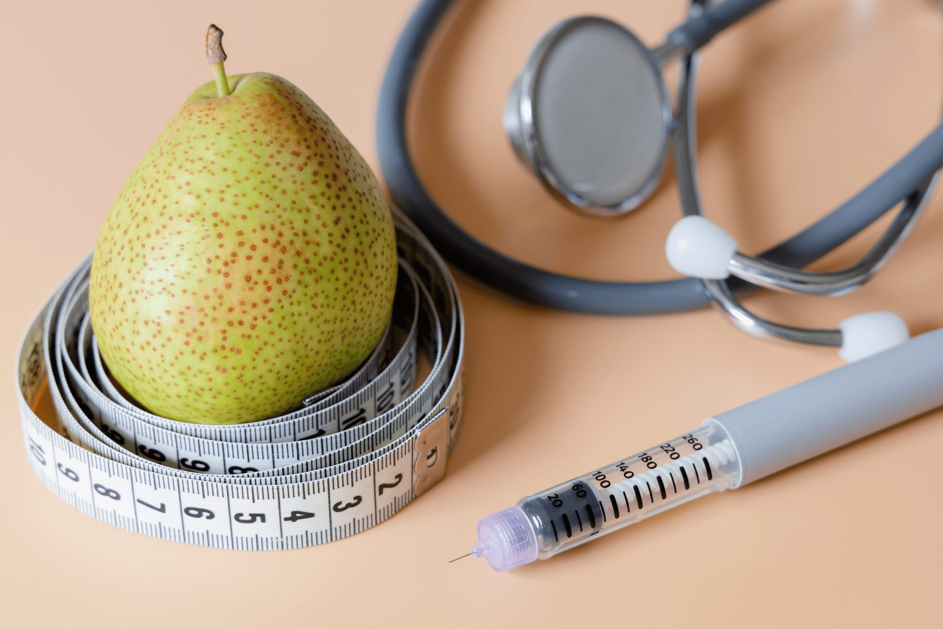 A pear wrapped in a measuring tape beside a syringe and stethoscope, symbolizing weight and metabolic health.
