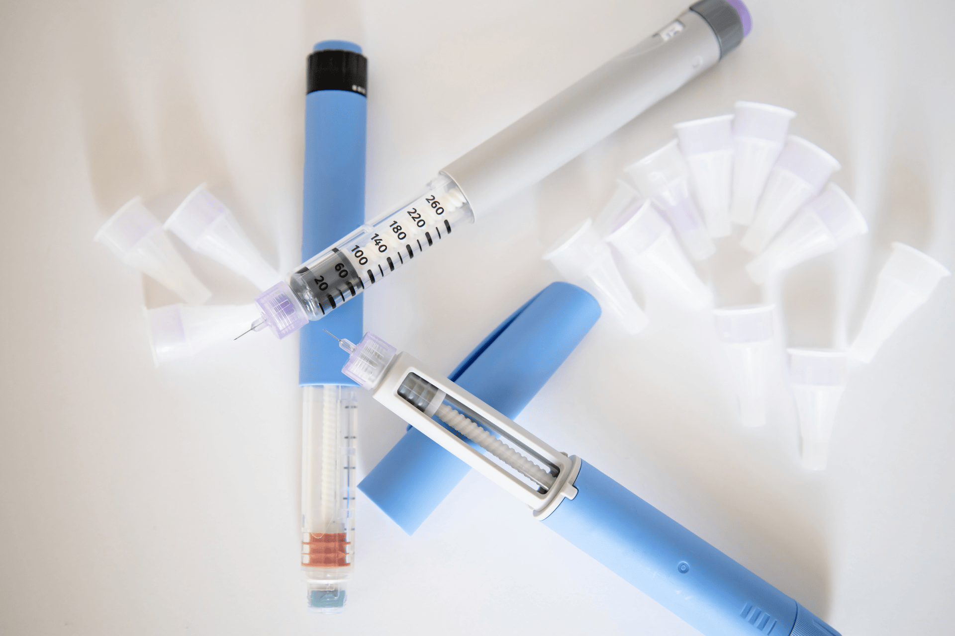 Two insulin pens with visible dosage markings and disposable needle tips on a white background.