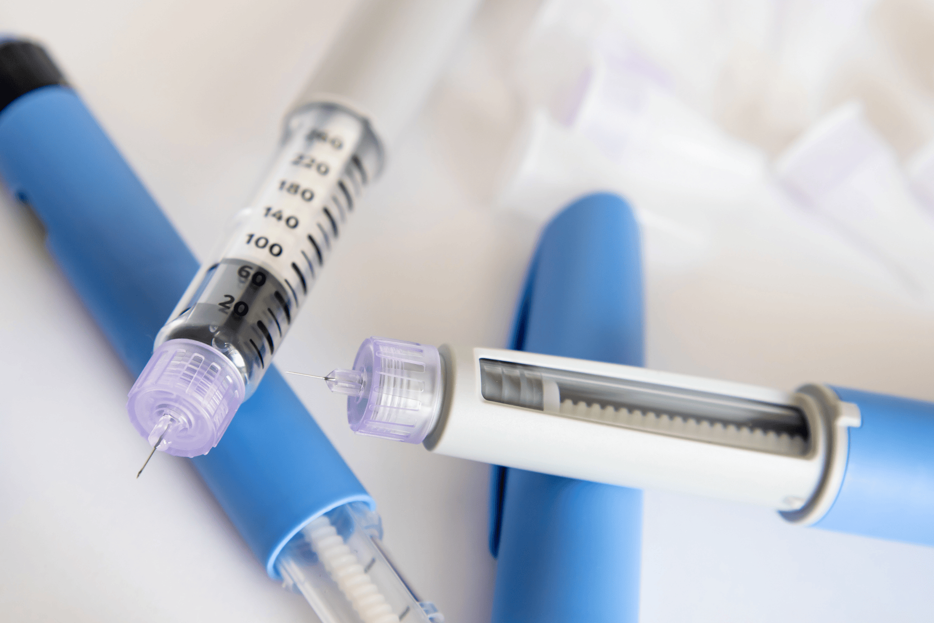 Close-up of insulin syringes and pen needles on a light background.