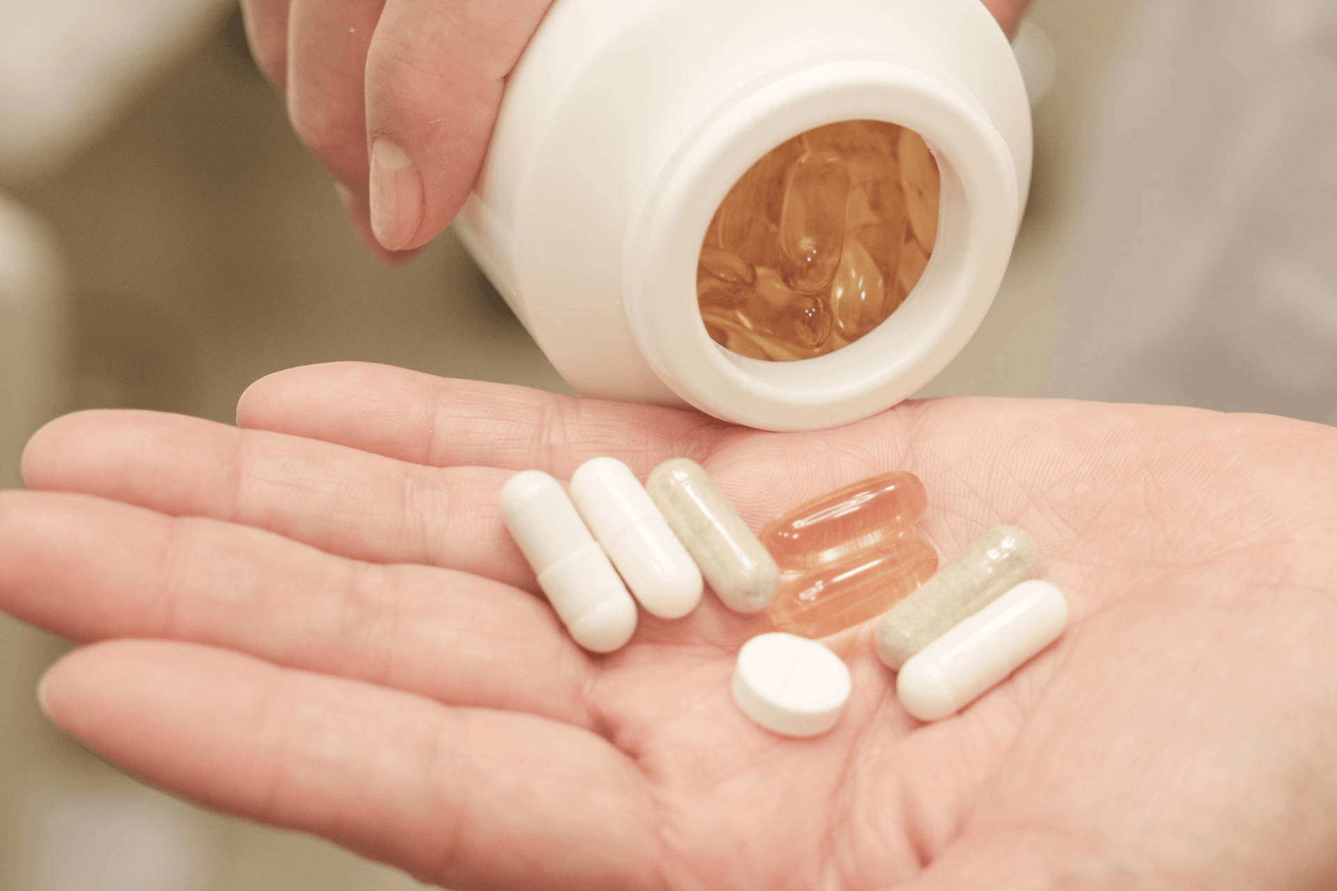 A hand holding several pills and natural supplements.