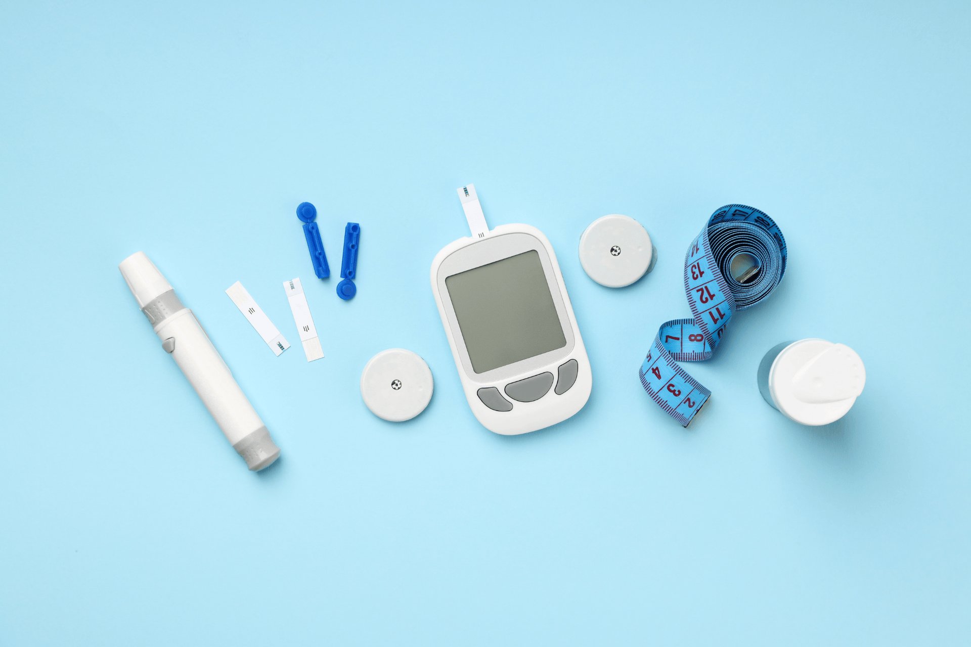 Diabetes testing supplies, including a glucose meter, test strips, a lancing device, and measuring tape on a blue background.
