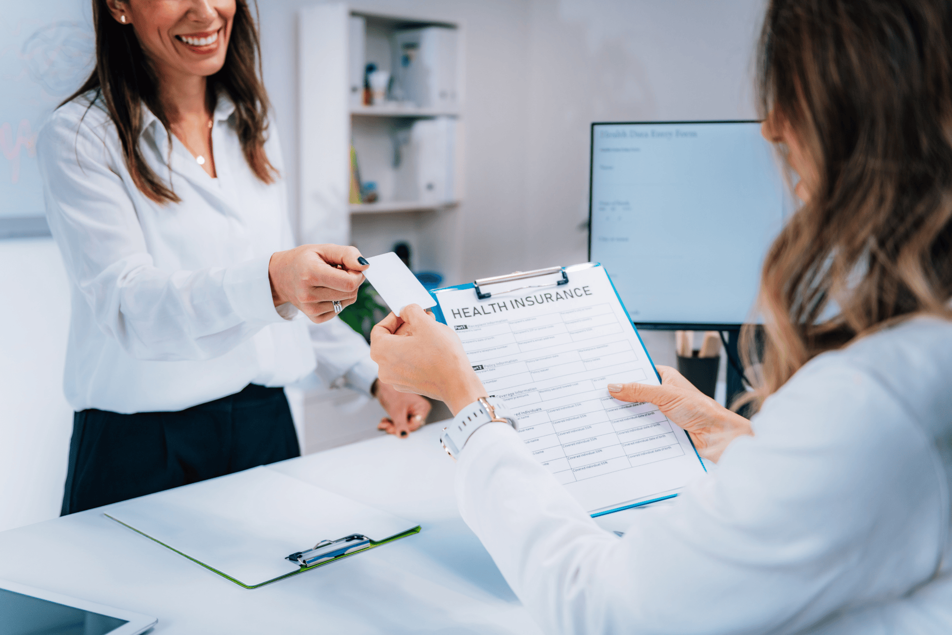 Patient and healthcare staff reviewing and exchanging health insurance information at a clinic.
