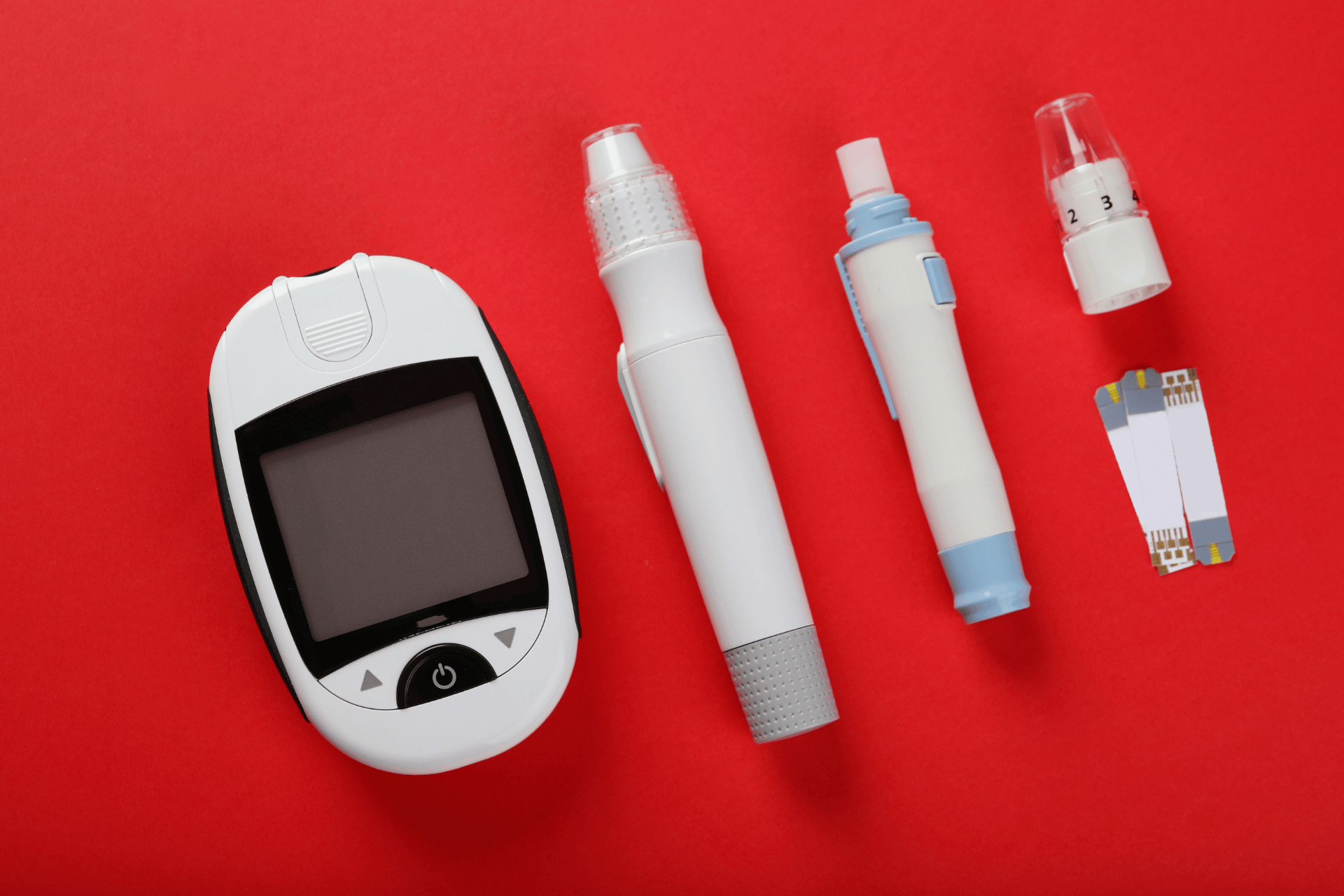 Blood glucose meter, lancing devices, and test strips on a red background.