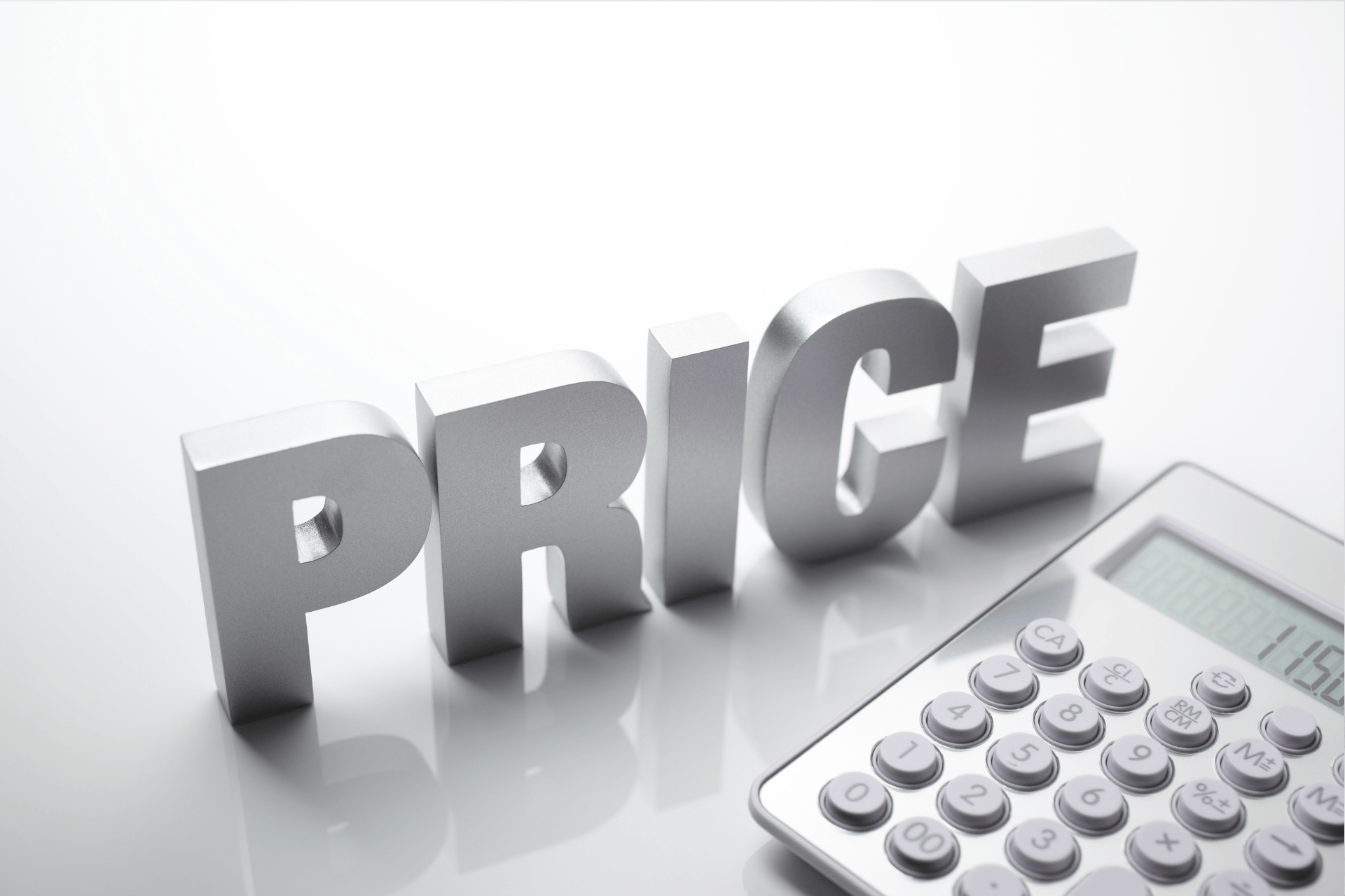 Word ‘PRICE’ in metallic letters next to a calculator on a white surface.