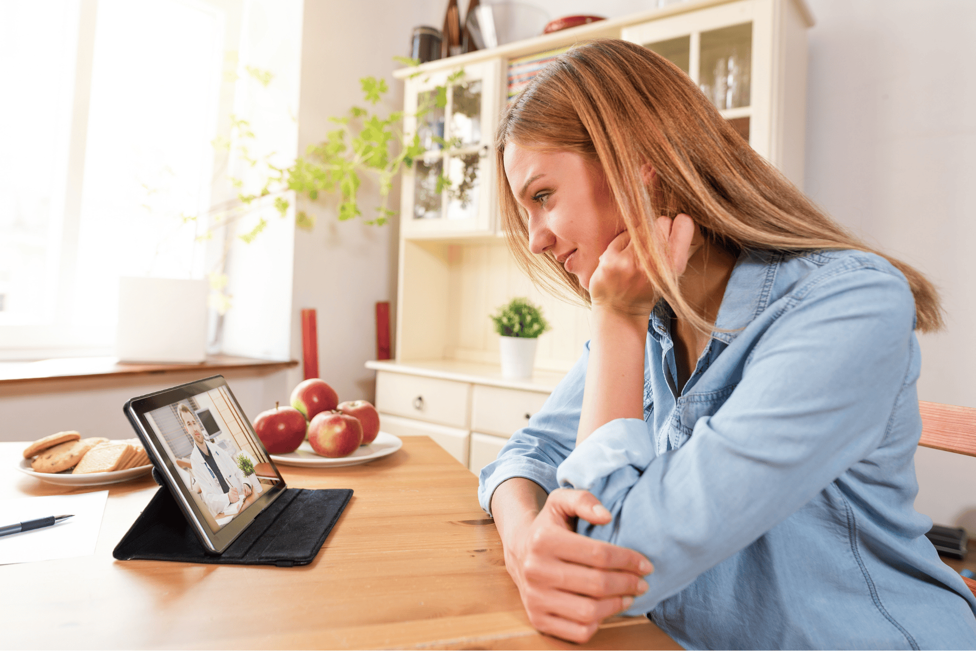 Woman smiling during an online video consultation with a doctor on a tablet.
