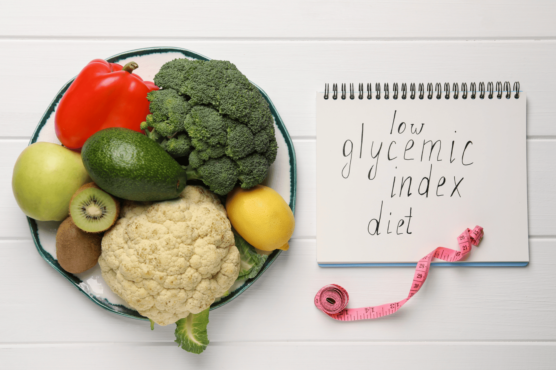 Fresh fruits and vegetables with a notebook labeled ‘low glycemic index diet.