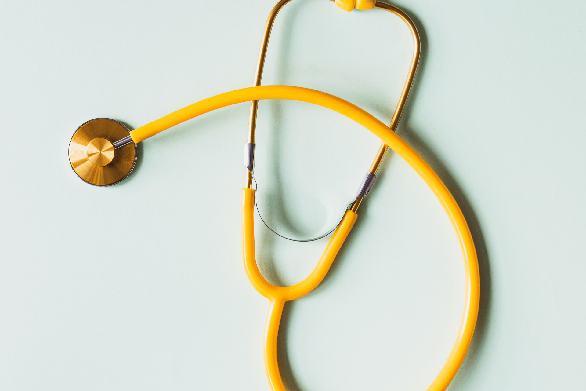 Yellow stethoscope on a light blue background.