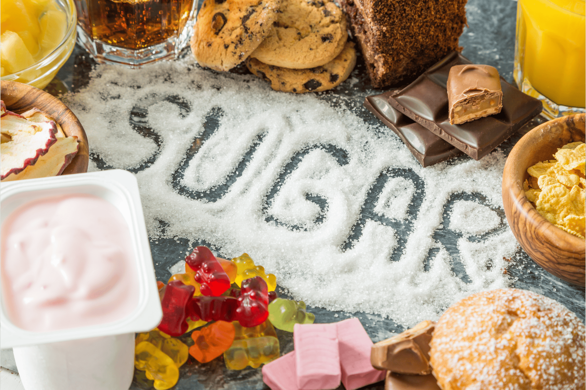 Word ‘SUGAR’ written in granulated sugar surrounded by sweets, chocolate, and desserts.