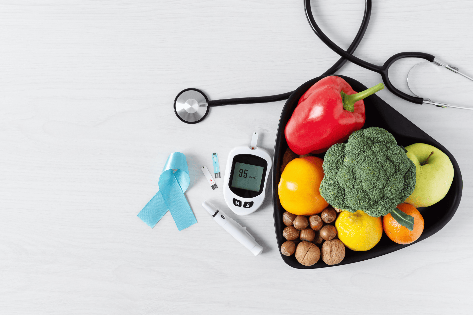 Healthy foods, glucose meter, stethoscope, and blue ribbon symbolizing diabetes awareness.
