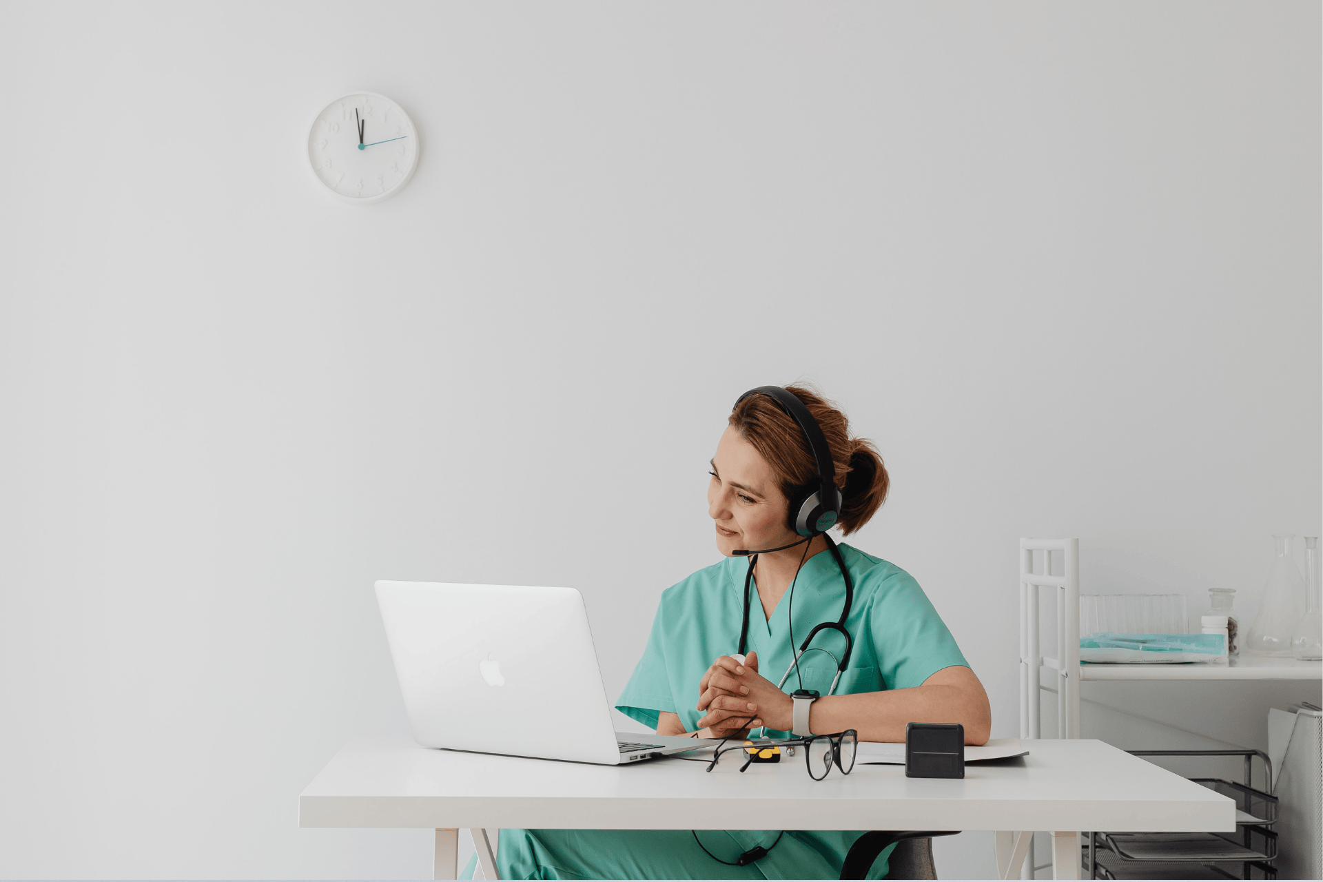 Nurse wearing headset talking to a patient through a video call on a laptop.