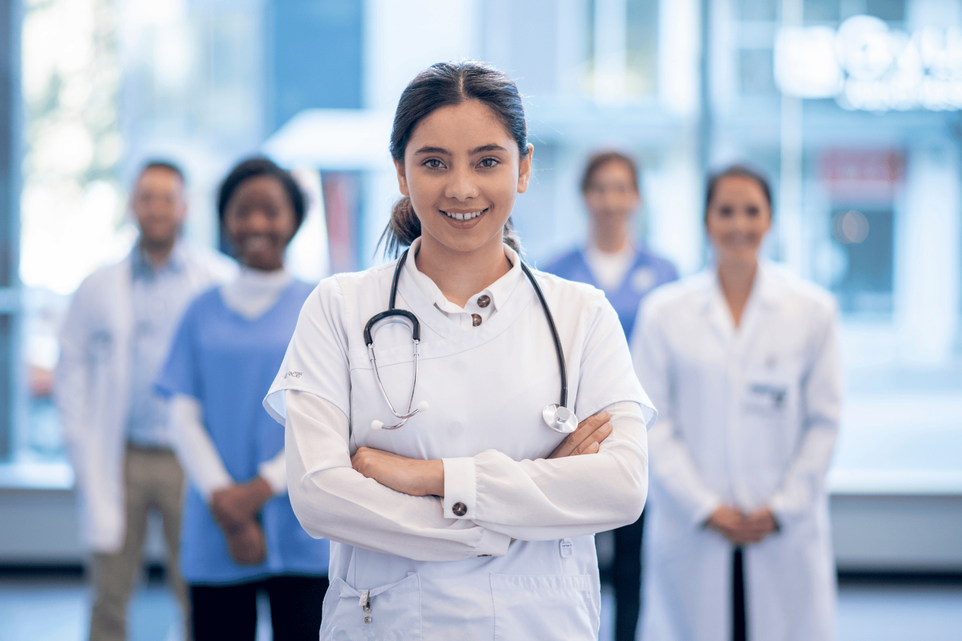 Confident healthcare professional standing with arms crossed in front of a diverse medical team