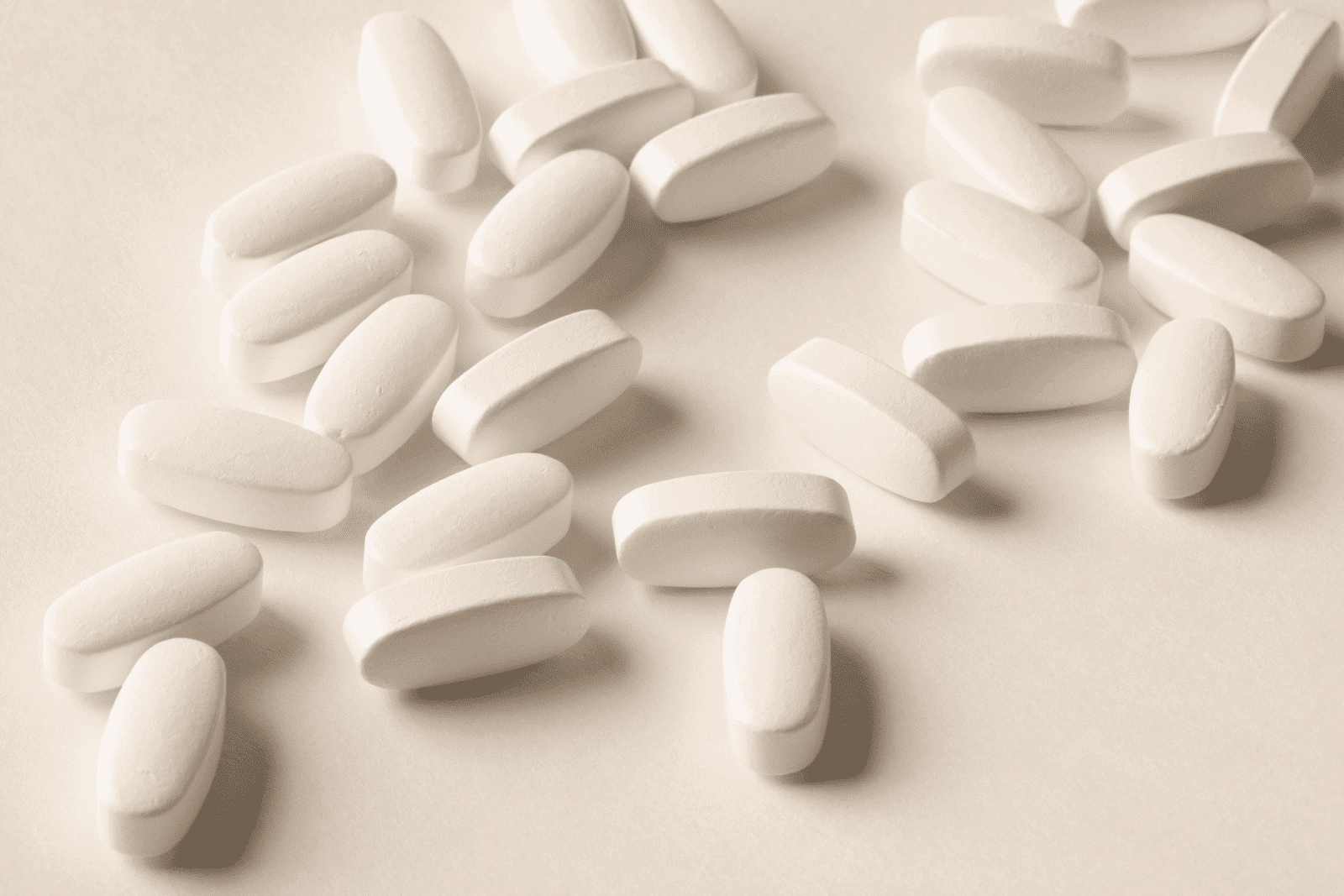 White oblong tablets scattered across a light surface.