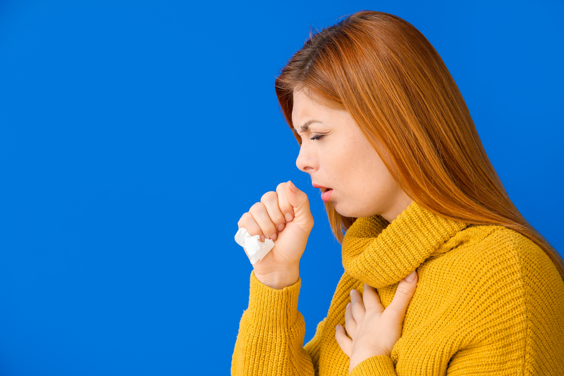 Woman coughing into her hand while holding her chest, appearing ill