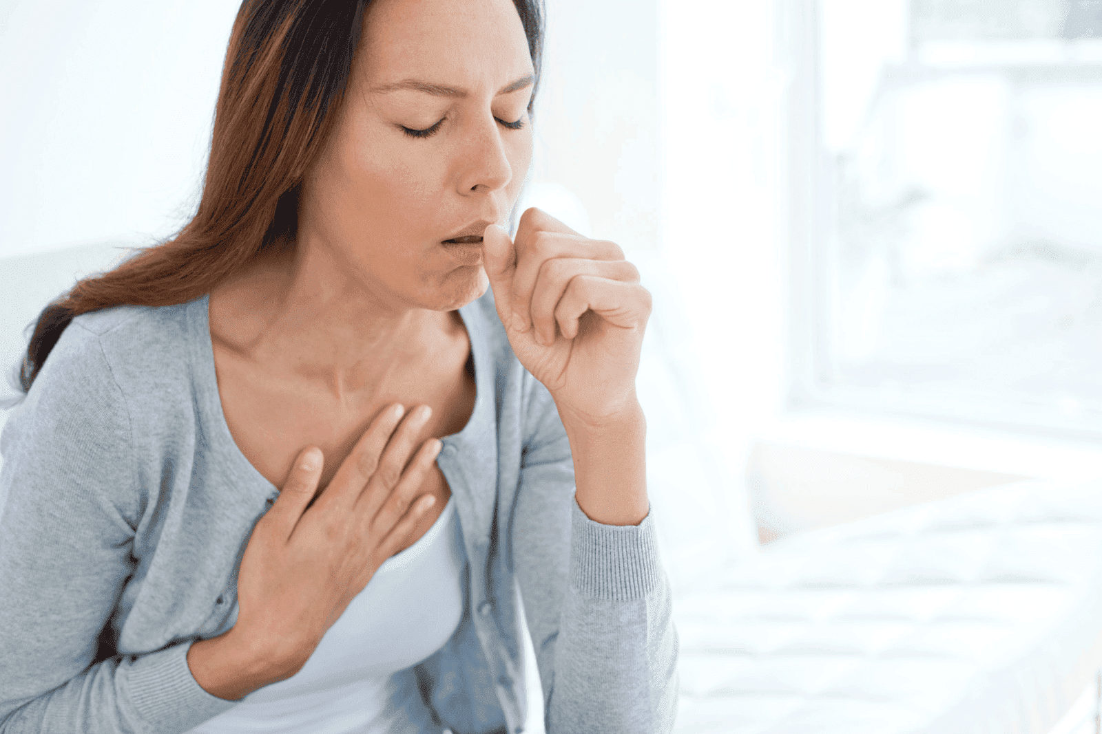 Woman coughing with hand on her chest