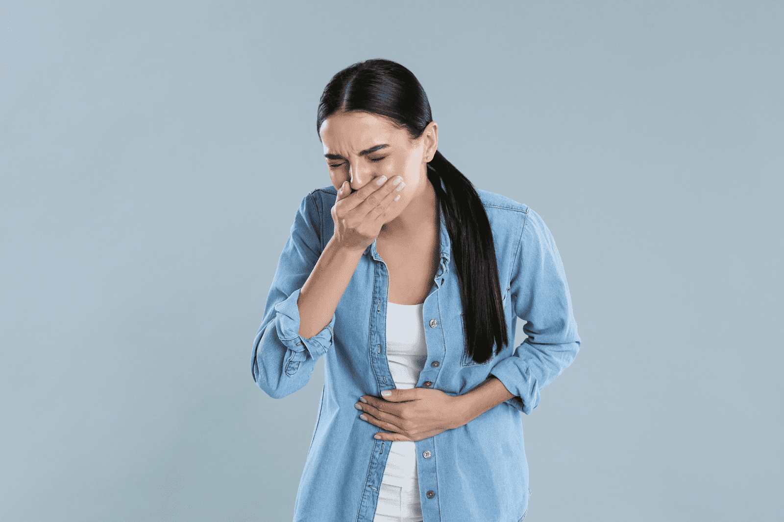 Woman covering her mouth and holding her stomach, appearing nauseous.