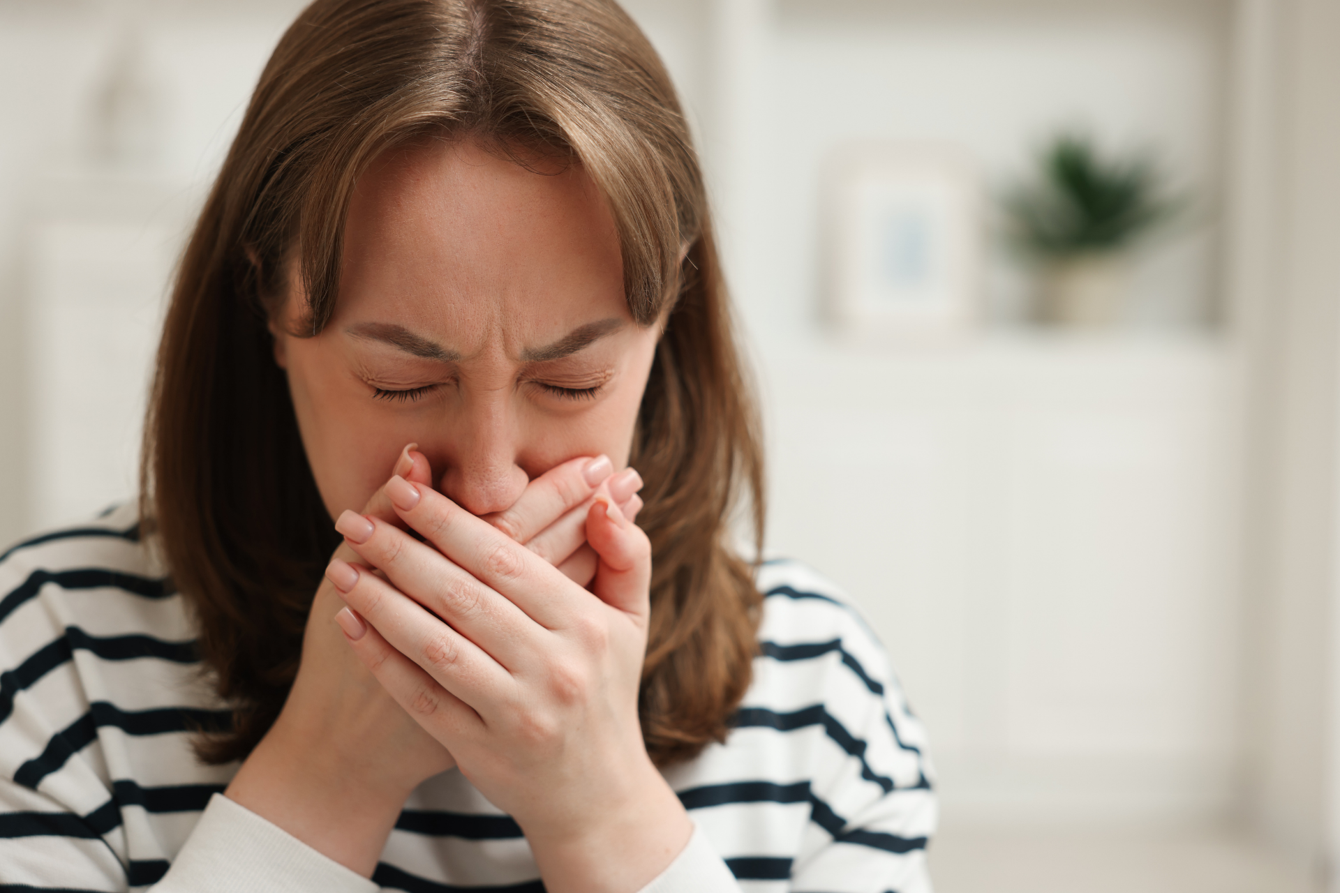 Woman covering her mouth with her hands, appearing nauseous