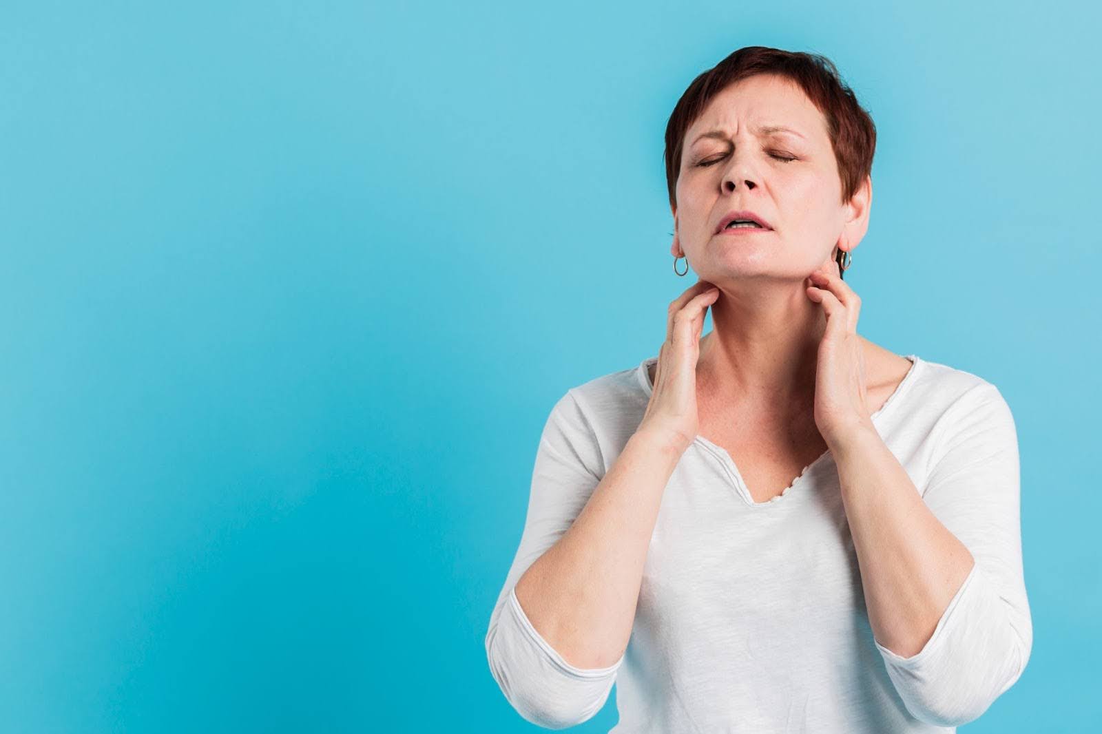 A woman feeling throat pain