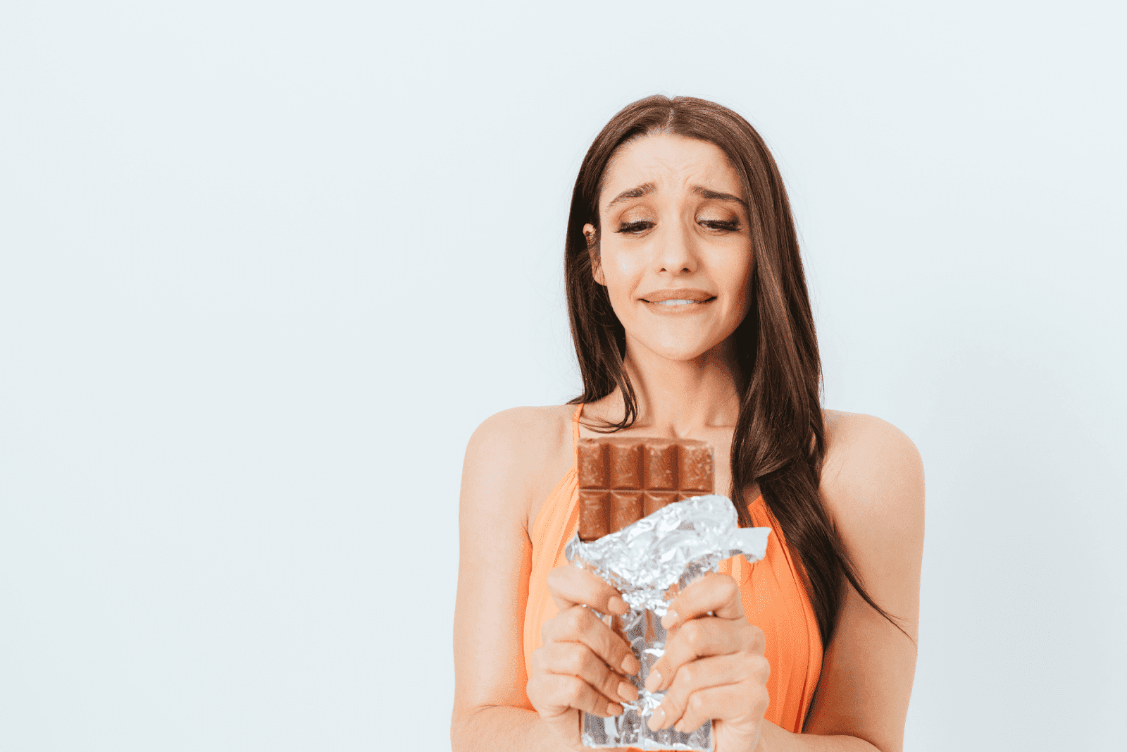 Woman holding a chocolate bar with a guilty expression
