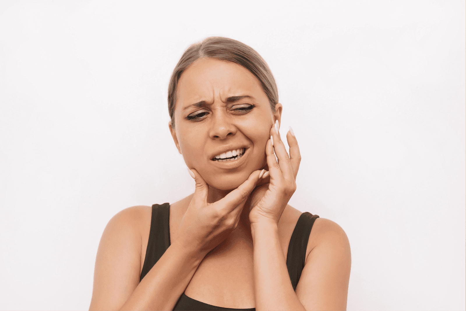 Woman holding her jaw with a painful expression, indicating jaw pain