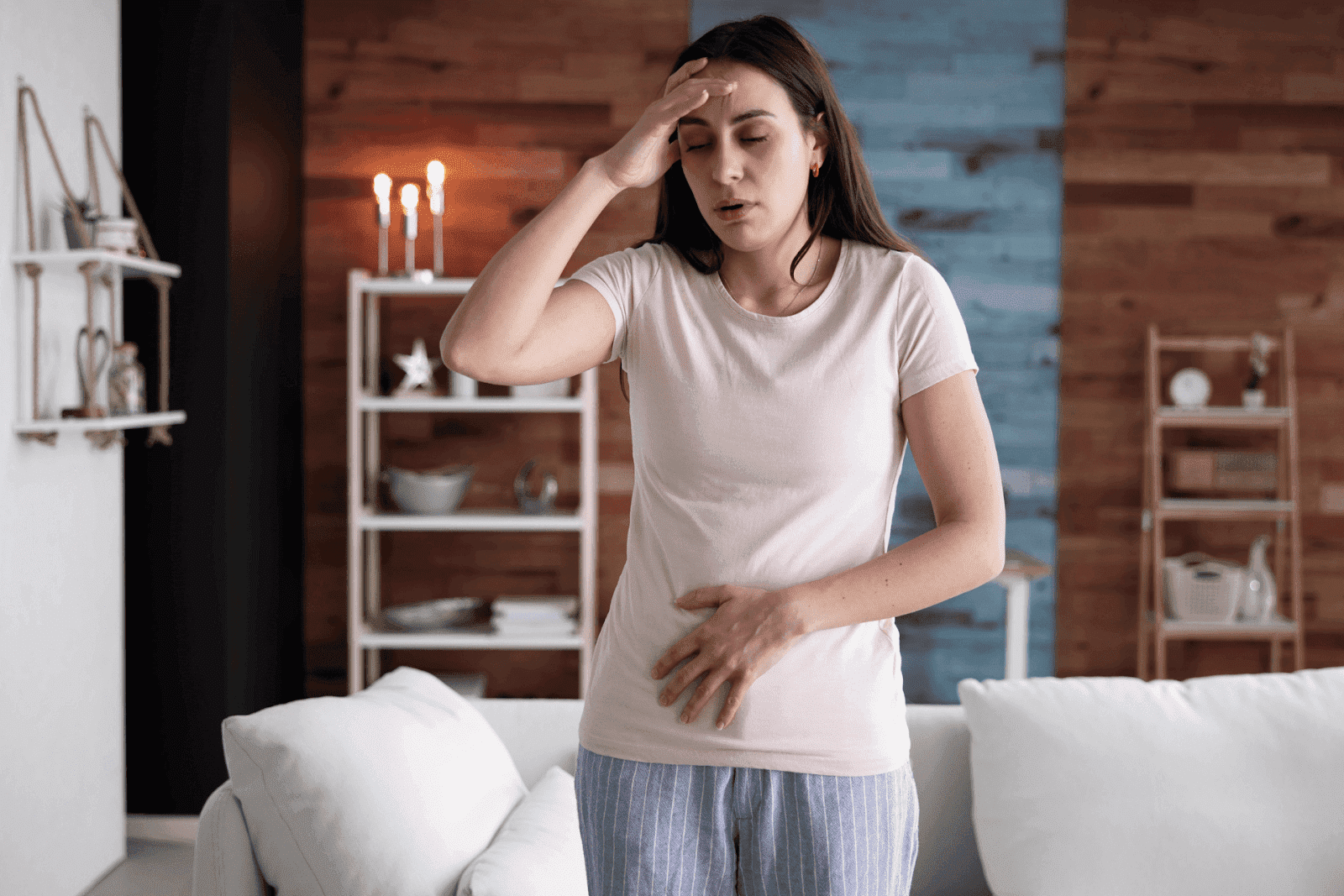 Woman holding stomach and forehead feeling unwell.