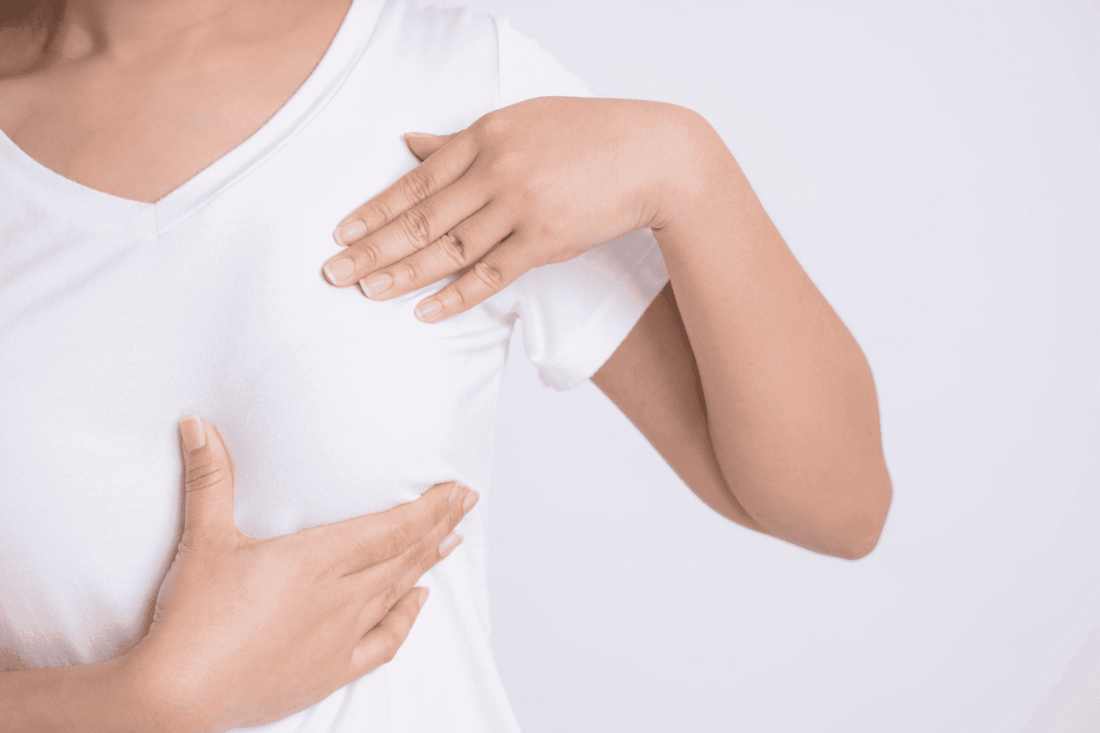 Woman in white shirt performing breast self-exam