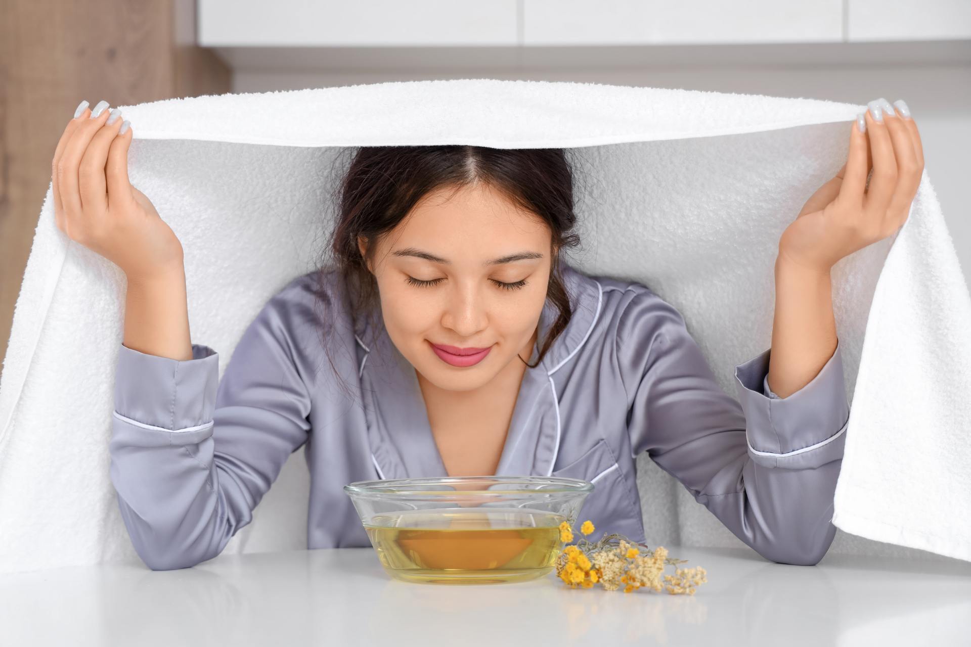 Woman inhaling steam from a bowl while holding a towel over her head