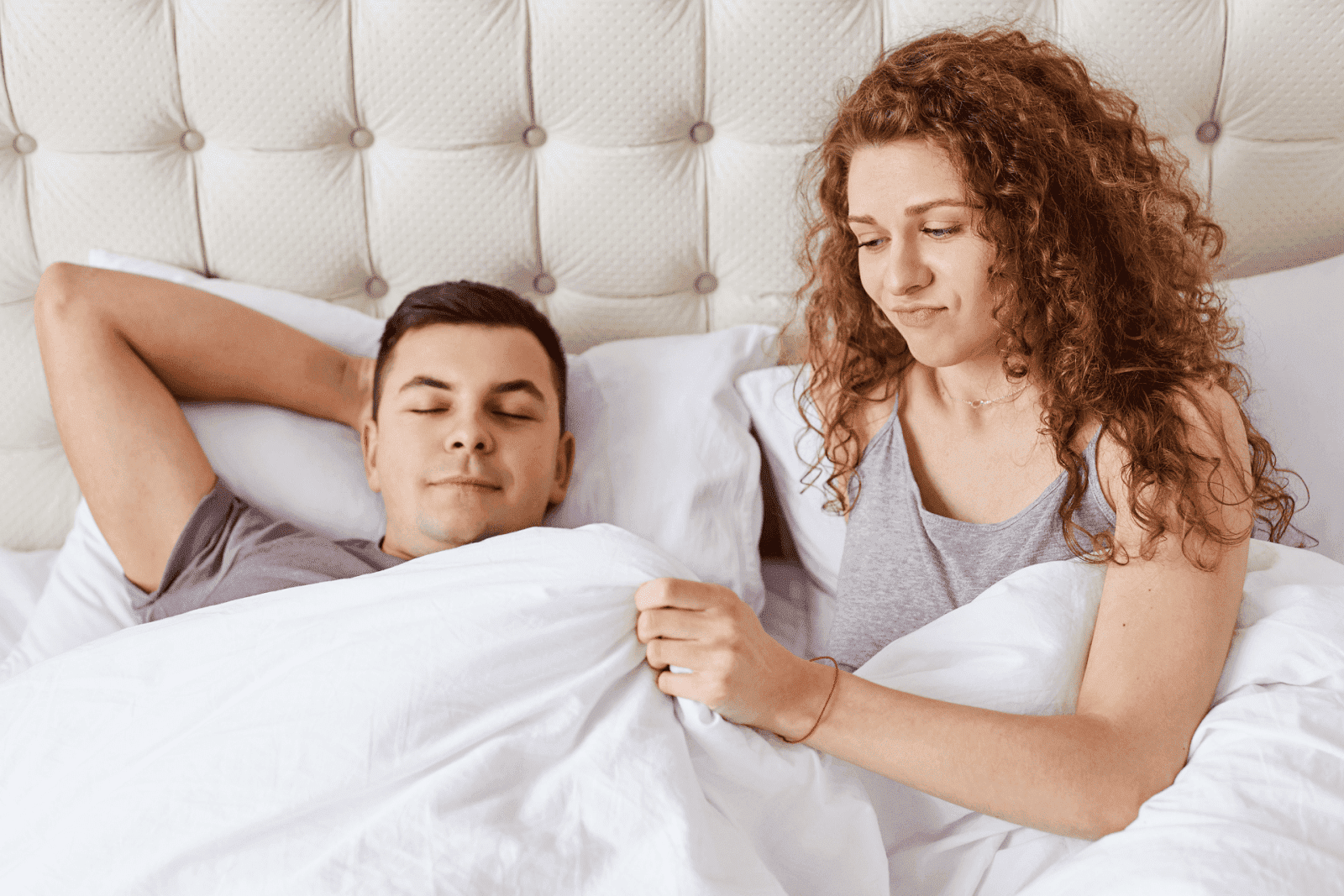 Woman looking frustrated beside her partner in bed, suggesting relationship tension related to erectile dysfunction.