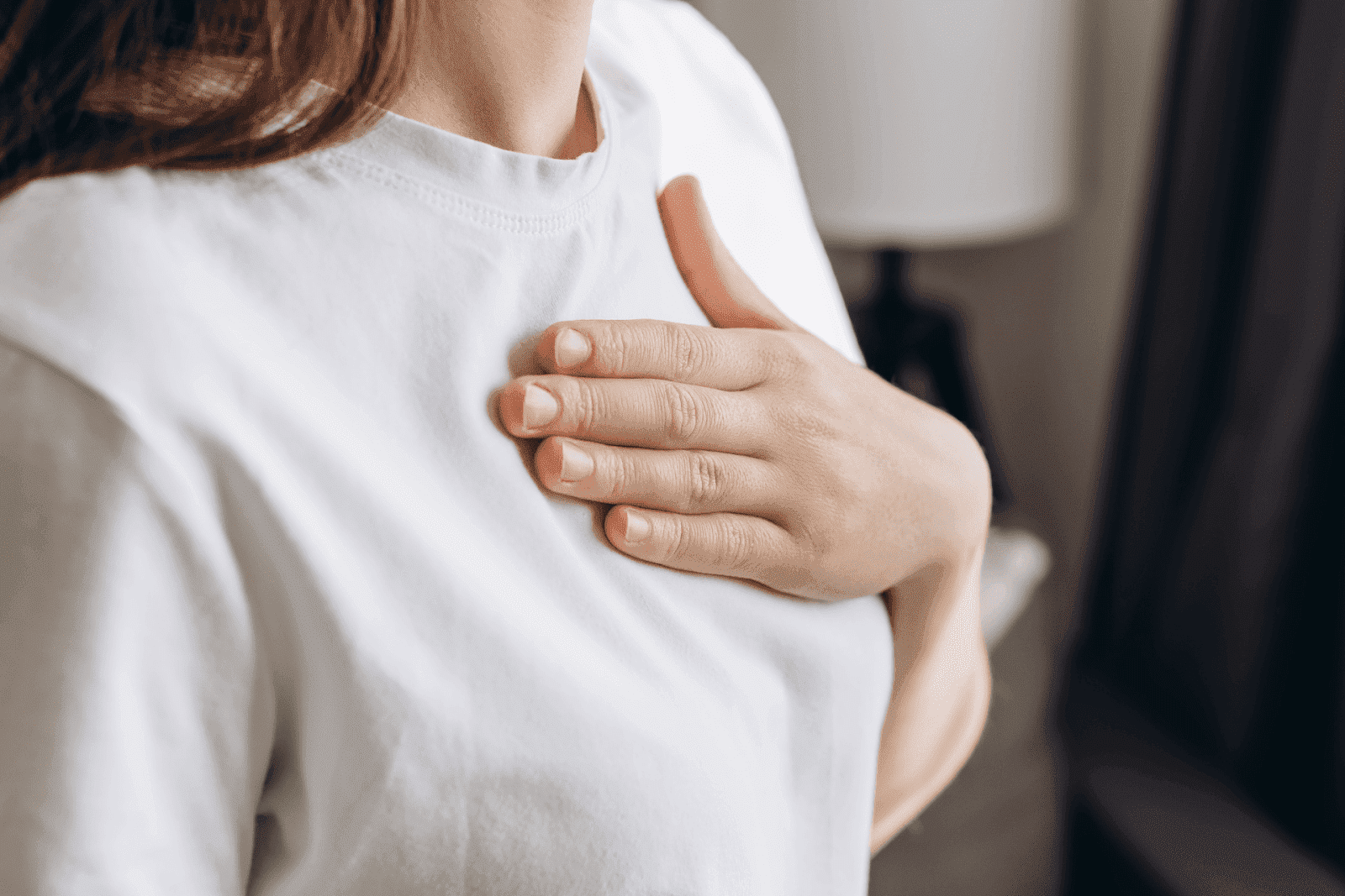Woman placing hand on her chest, appearing to experience discomfort.