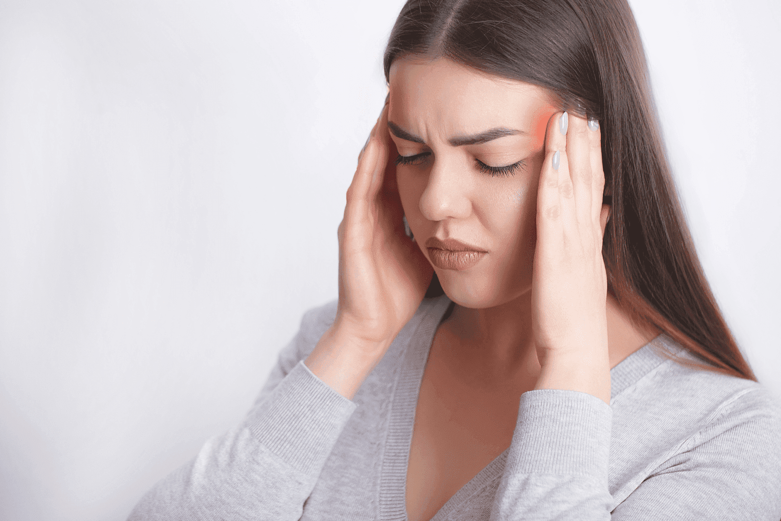 Woman pressing temples, showing signs of a headache.