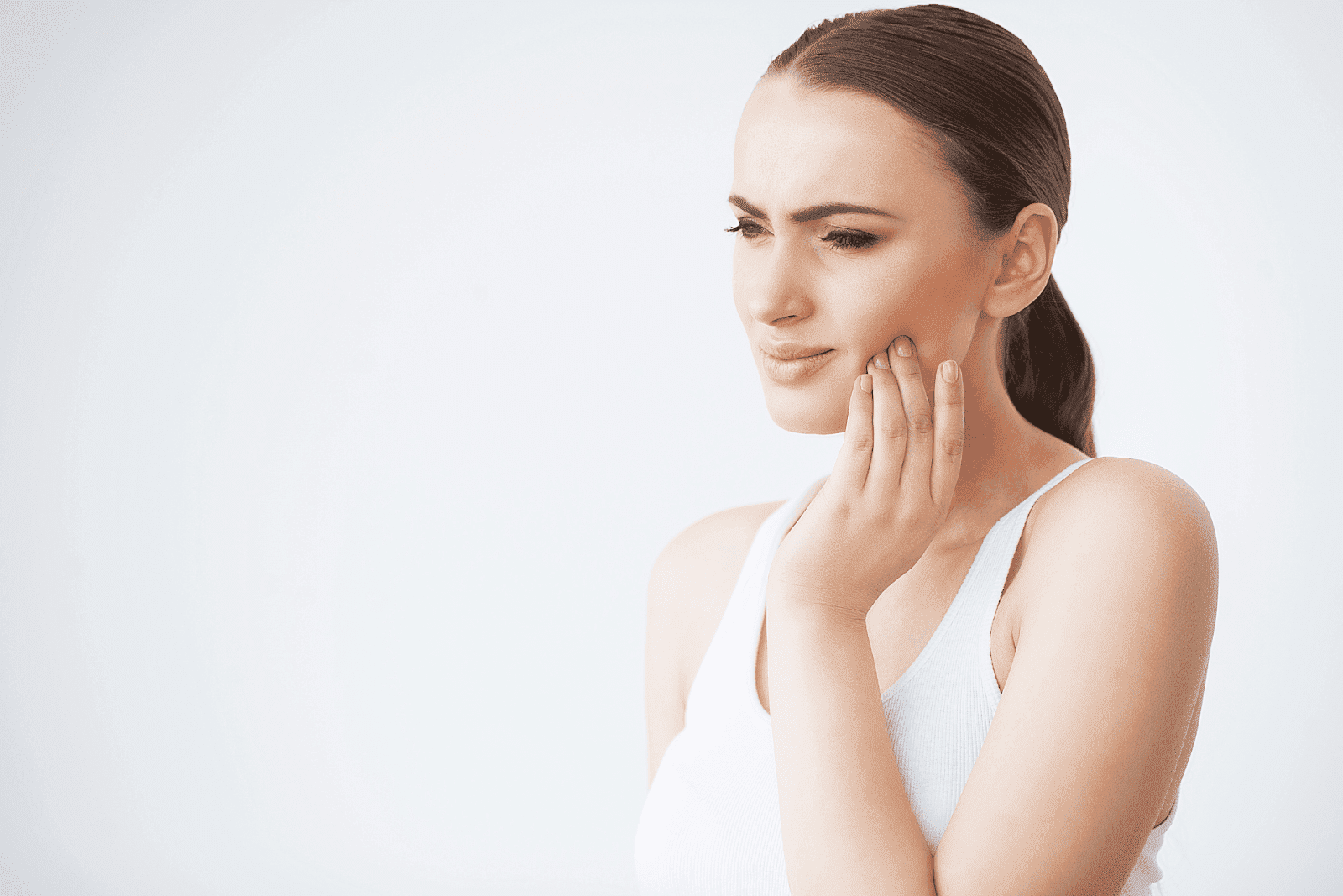 Woman touching her cheek with a painful expression, indicating a toothache
