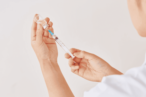 Medical professional drawing liquid from a vial with a syringe