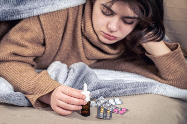 Young sick woman laying on her bed with medicine