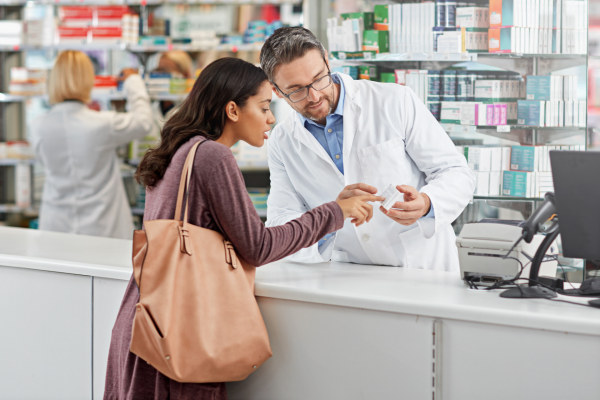 A pharmacist explains medication to a woman at a pharmacy counter
