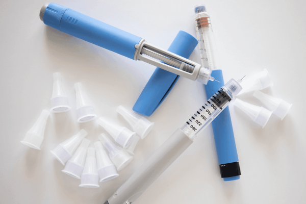 Insulin pens and needle tips arranged on a white surface