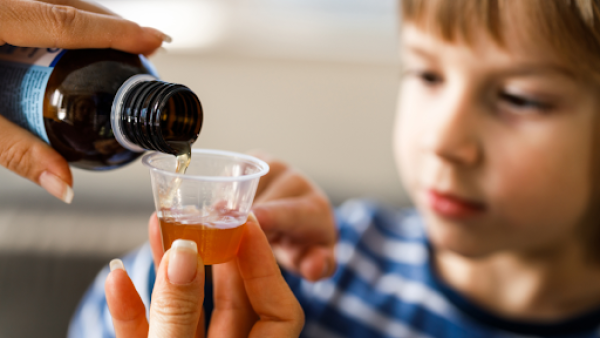 Person pouring cough syrup for child