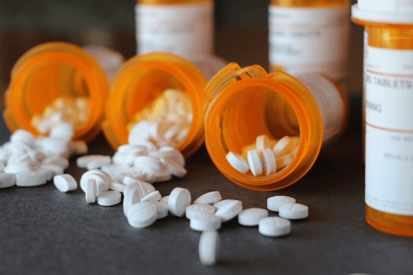 Prescription pill bottles tipped over with white tablets spilling out