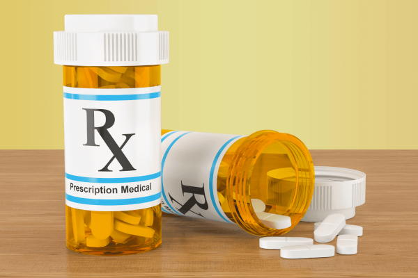 Two prescription pill bottles with tablets on a wooden surface