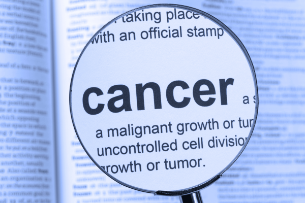 Magnifying glass highlighting the word ‘cancer’ in a dictionary definition.